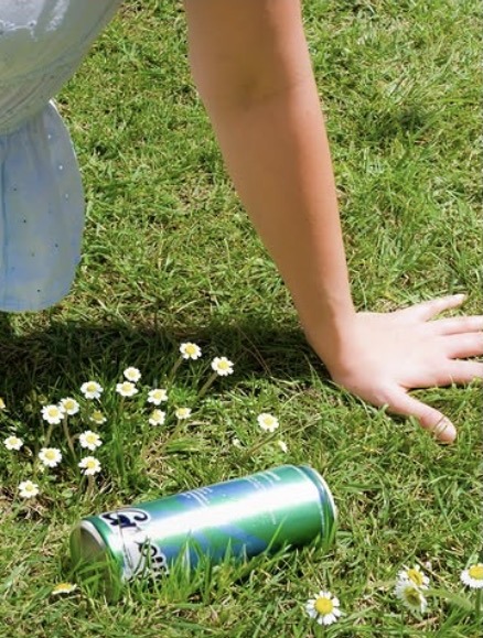 Green Groovy Unwind can resting in the grass among daisies