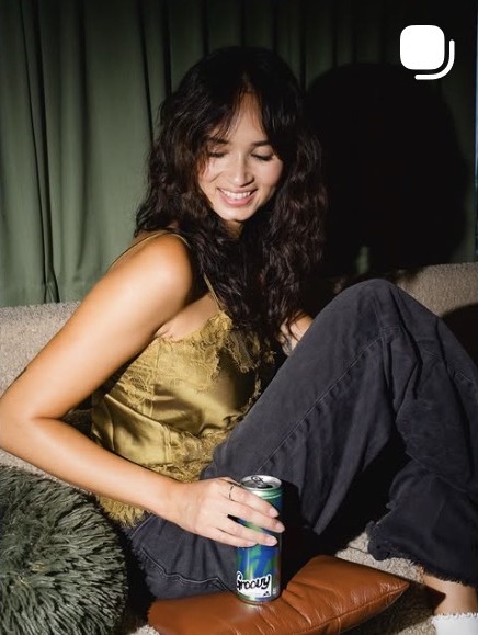 Woman relaxing on a sofa holding a Groovy can