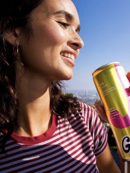 Woman smiling in the sun holding a Groovy can